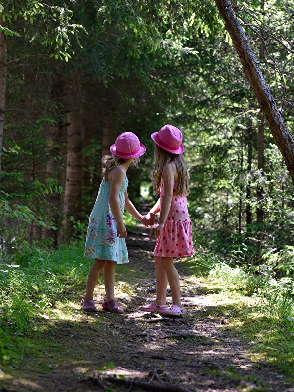 Una niña en un bosque con un sombrero azul y un corazón en medio.