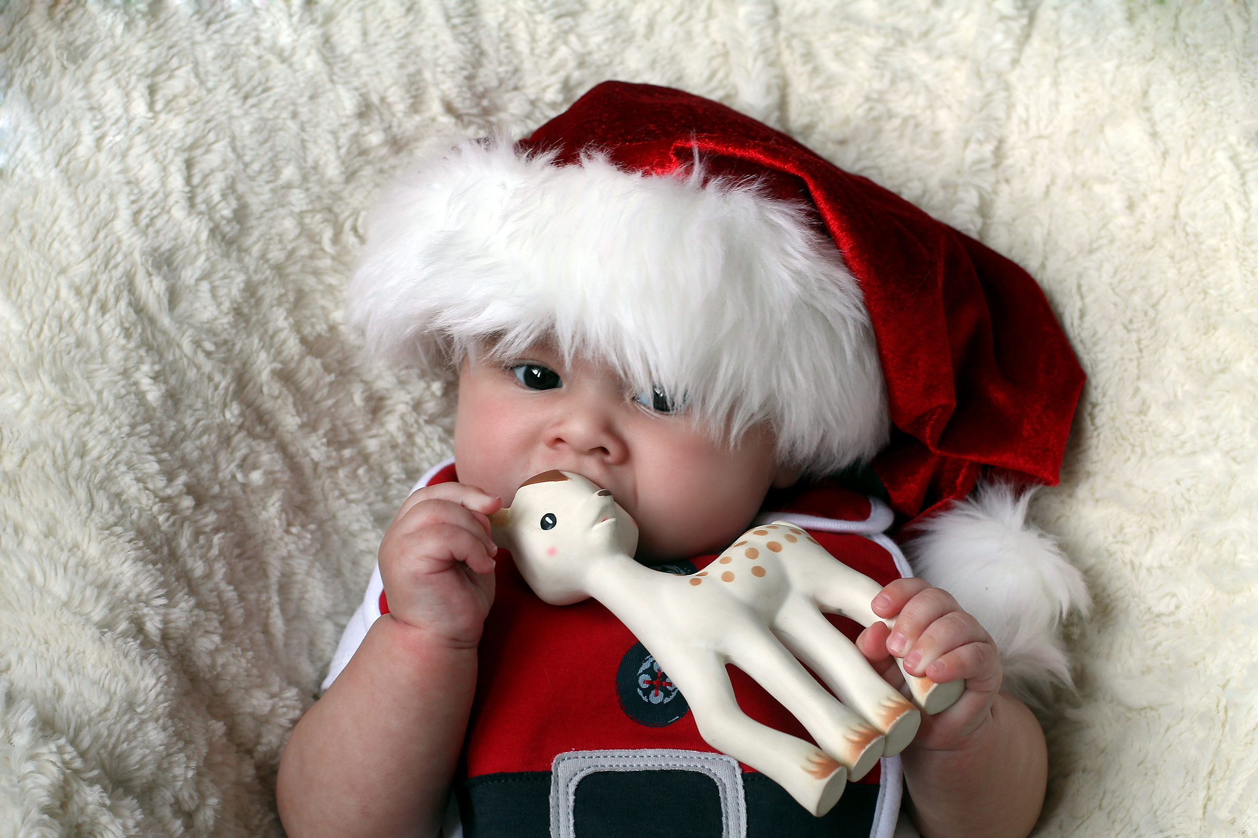 Santa baby. Фото ребенок в шапке с игрушками.